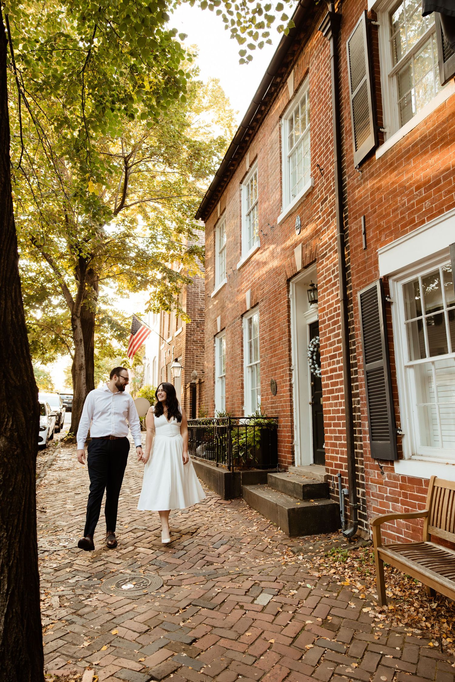 A bride and groom walk along a wooden marina dock with a white yacht moored in the background.