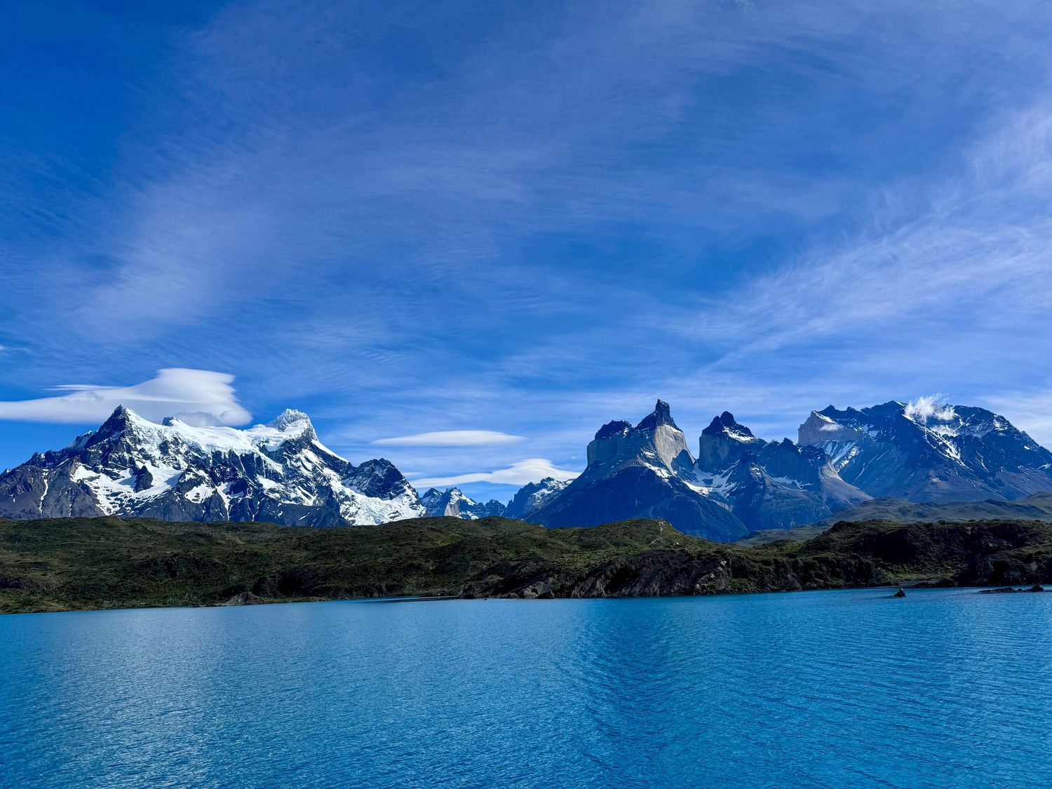 Stunning turquoise lake reflecting snow-capped Torres del Paine mountains under blue sky in Patagonia, Chile.