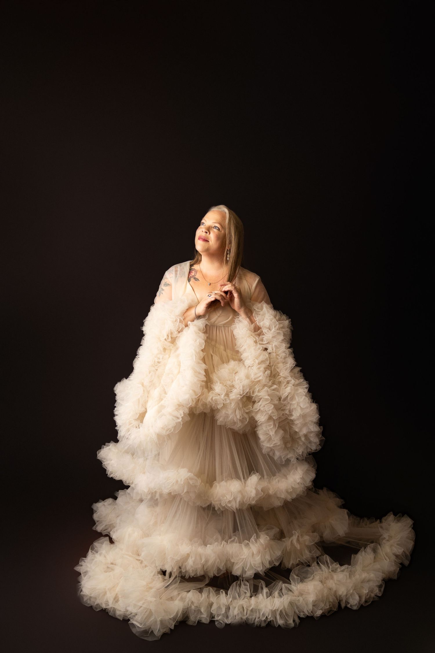 Dramatic studio portrait featuring flowing ivory ruffled dress against black background in Bothell Filling the Frame Photography Studio.