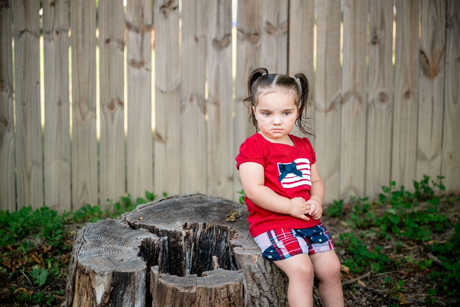 Toddler in plaid shirt at a festive hot cocoa bar stand decorated with holiday garland and bunting.
