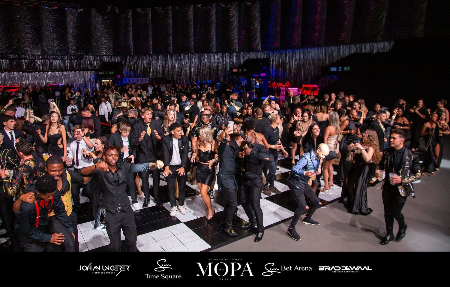 Elegant MOPA 2025 gala event with guests dancing under colorful stage lights on a white dance floor.