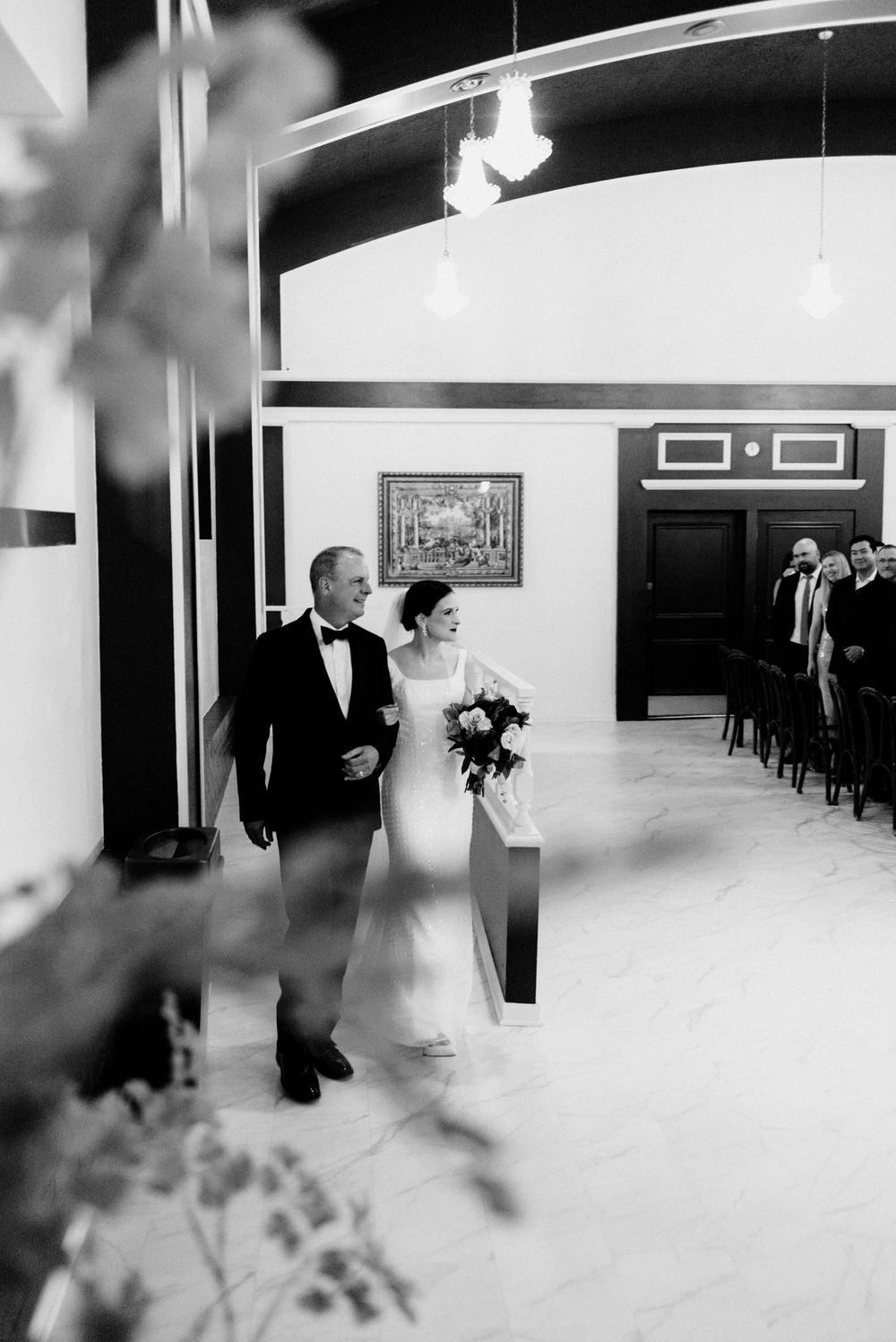 Black and white photo of a bride and her escort walking down the aisle in chic Milwaukee wedding venue.