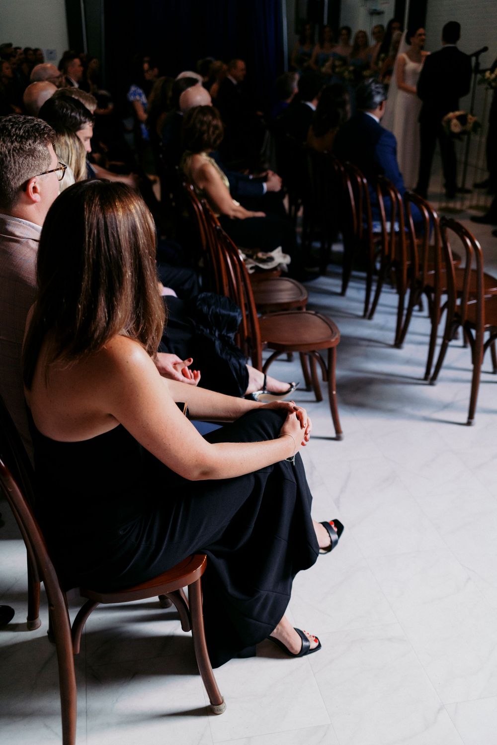 Window light illuminates guests in natural light wedding ceremony space.
