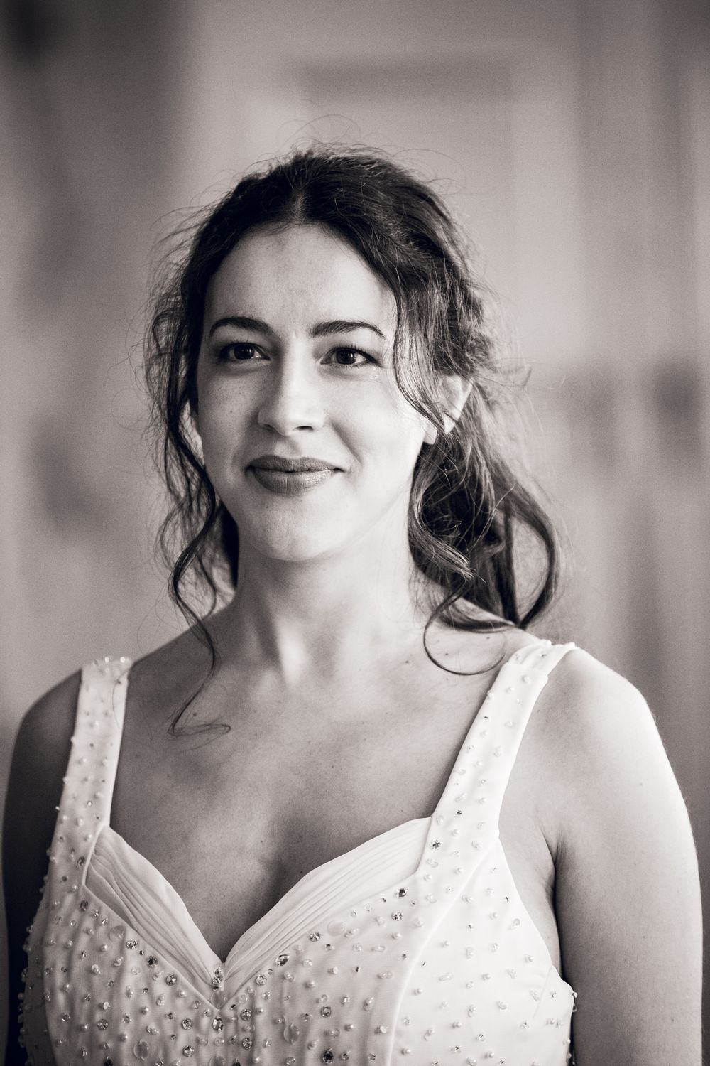 Black and white portrait of a smiling bride in a beaded white dress with elegant updo hairstyle.