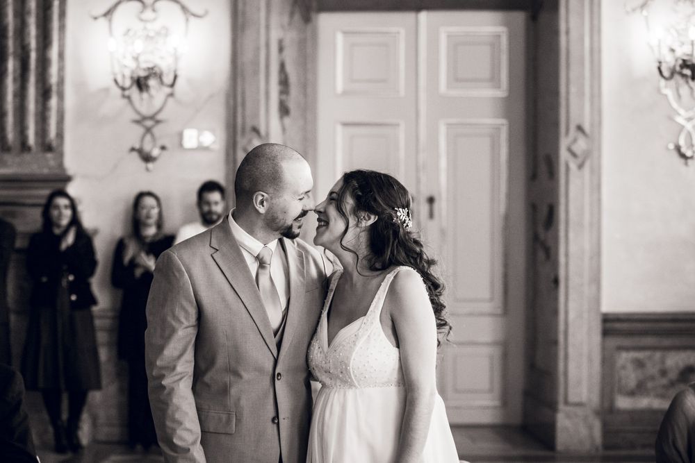 Black and white wedding photo of a bride and groom sharing a tender moment, about to kiss in an elegant venue.