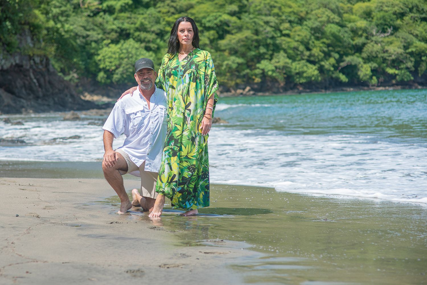 Man kneeling on one knee proposing to woman in orange dress outdoors near trees.