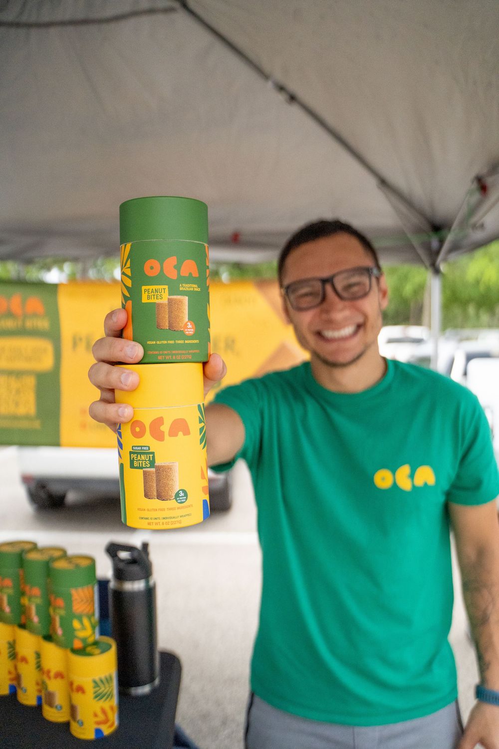 Display of Oca branded beverages with staff members wearing matching green shirts at an outdoor event.