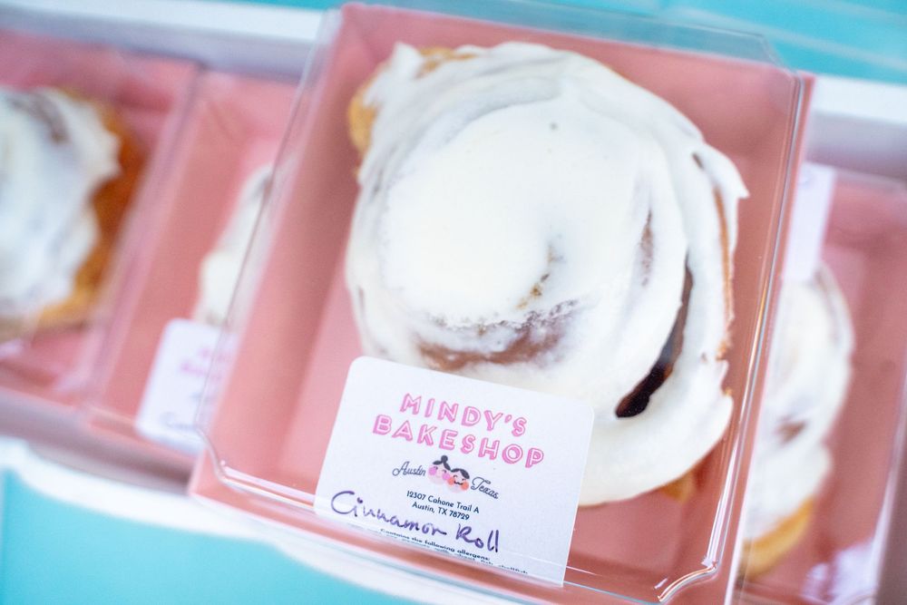 Pink and white frosted cupcakes or desserts displayed in clear plastic containers.