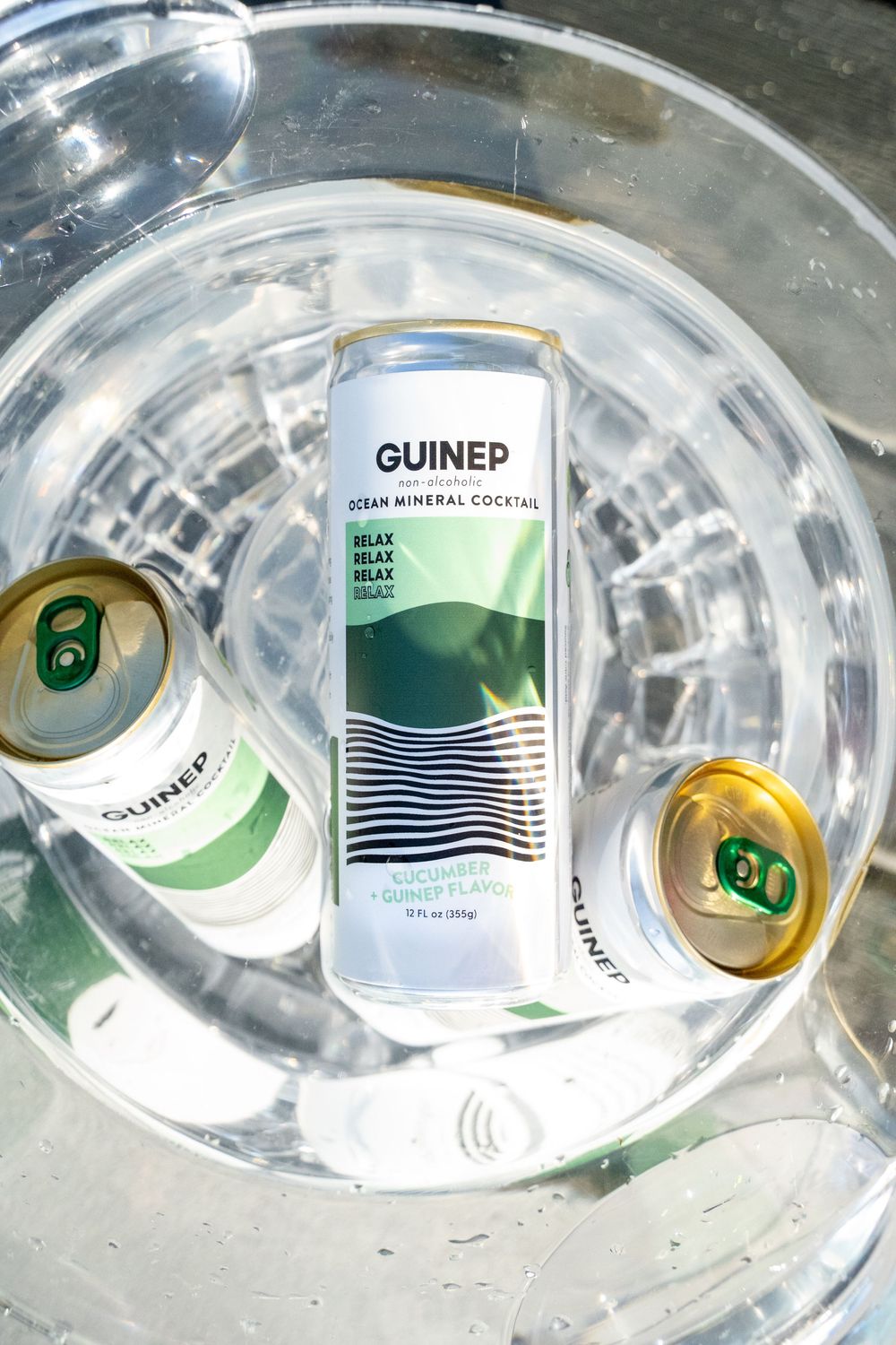 Empty crushed aluminum beverage cans with green and white designs arranged in a reflective surface.