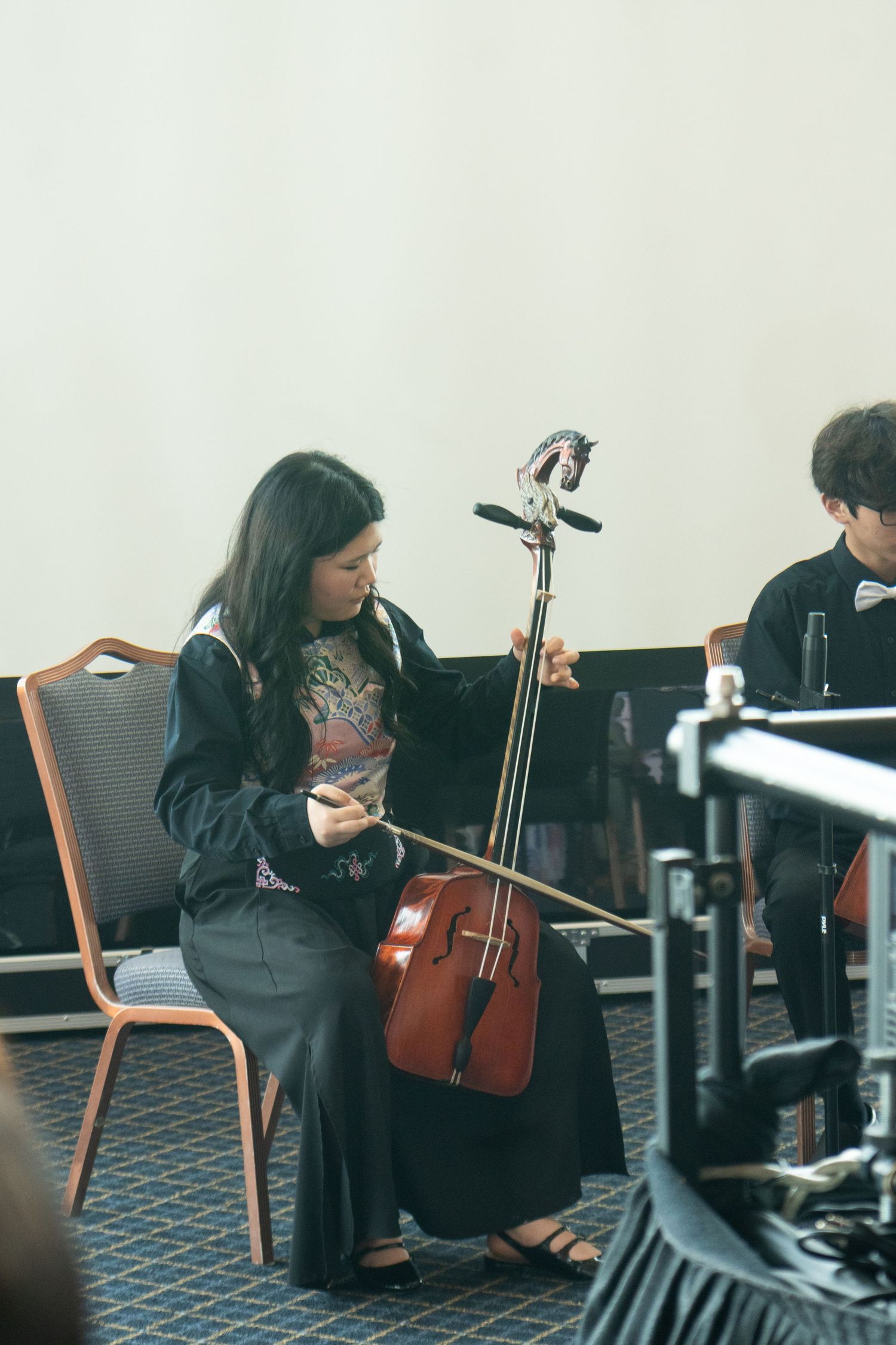 mongolian girl performing tradtional mongolian instrument at an event.