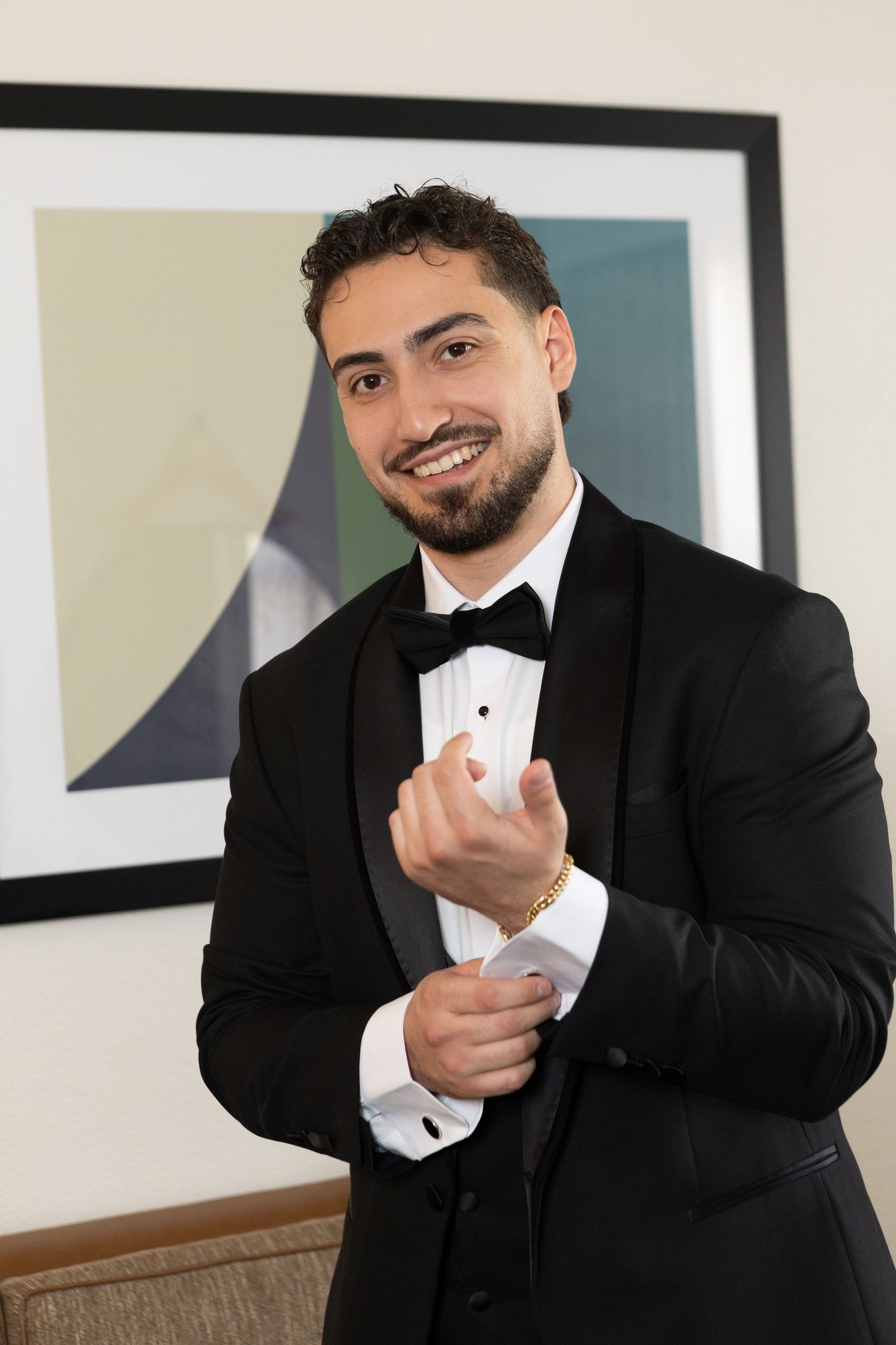 Groom adjusting his cufflinks while wearing a black tuxedo during wedding preparations at Glen Island Harbour Club in Westchester County.