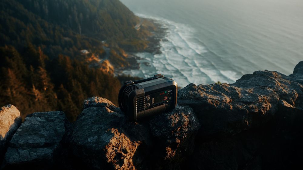 Action camera placed on rocky cliff overlooking scenic ocean coastline at golden hour.