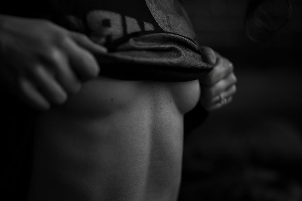 Black and white close-up photo of a person lifting their shirt to reveal toned abdominal muscles.