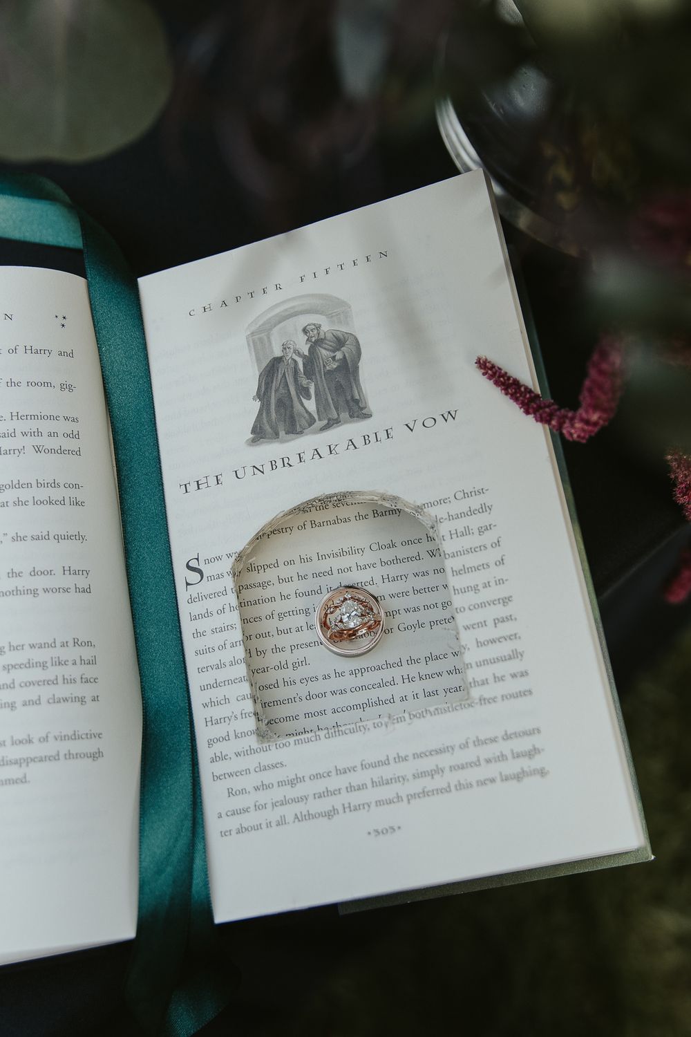 Close-up of wedding rings resting on harry potter book surrounded by dark florals