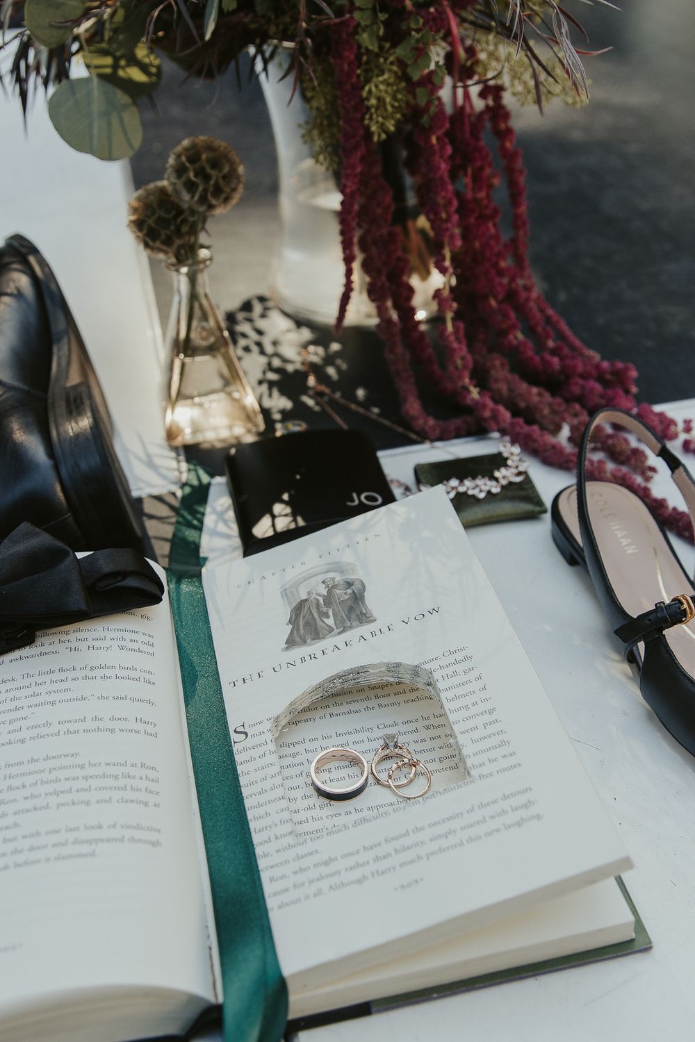 Close-up of wedding rings resting on harry potter book surrounded by dark florals