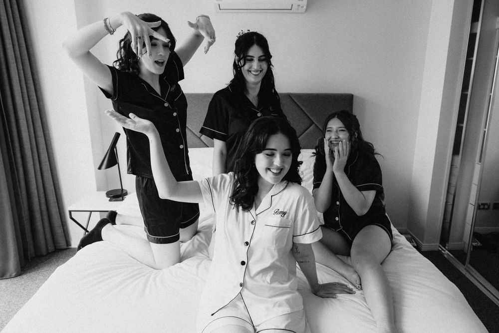 Group having fun and posing on a bed during wedding preparations.