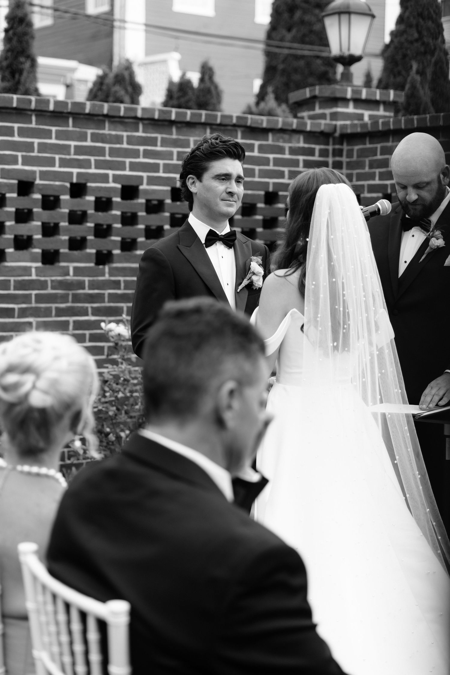 Black and white wedding ceremony photo showing a bride and groom exchanging vows at mansion venue in Rhode Island.