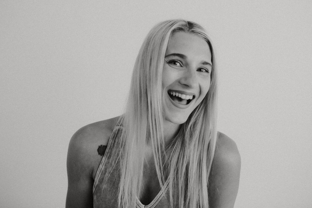 Black and white portrait of woman laughing against plain background.