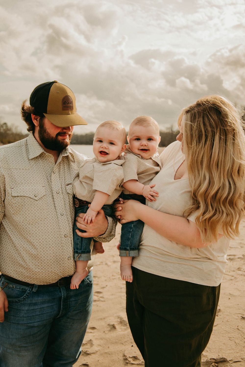 Family portrait with twin babies on beach at sunset.
