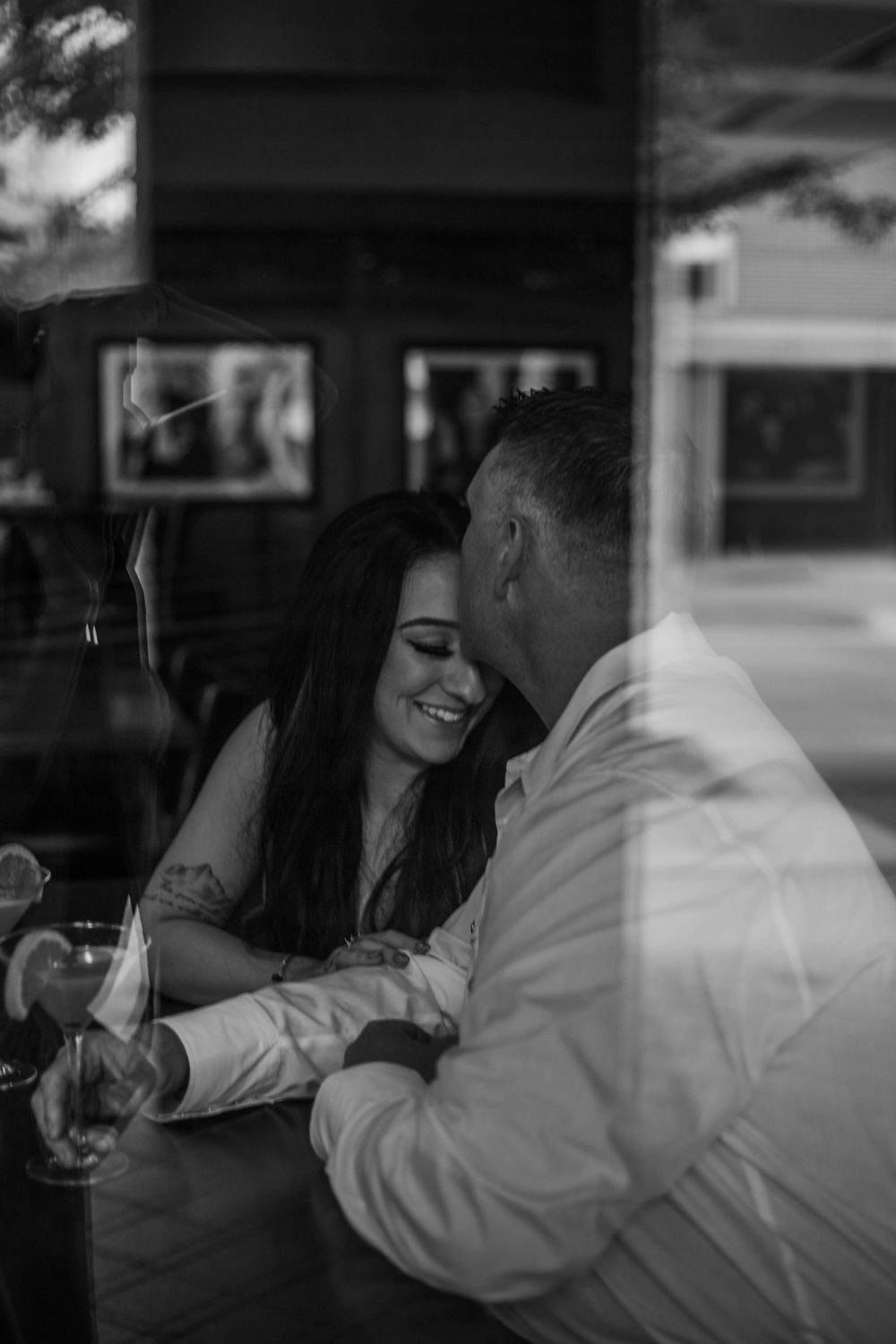Intimate black and white photo of couple sharing romantic moment at restaurant table.