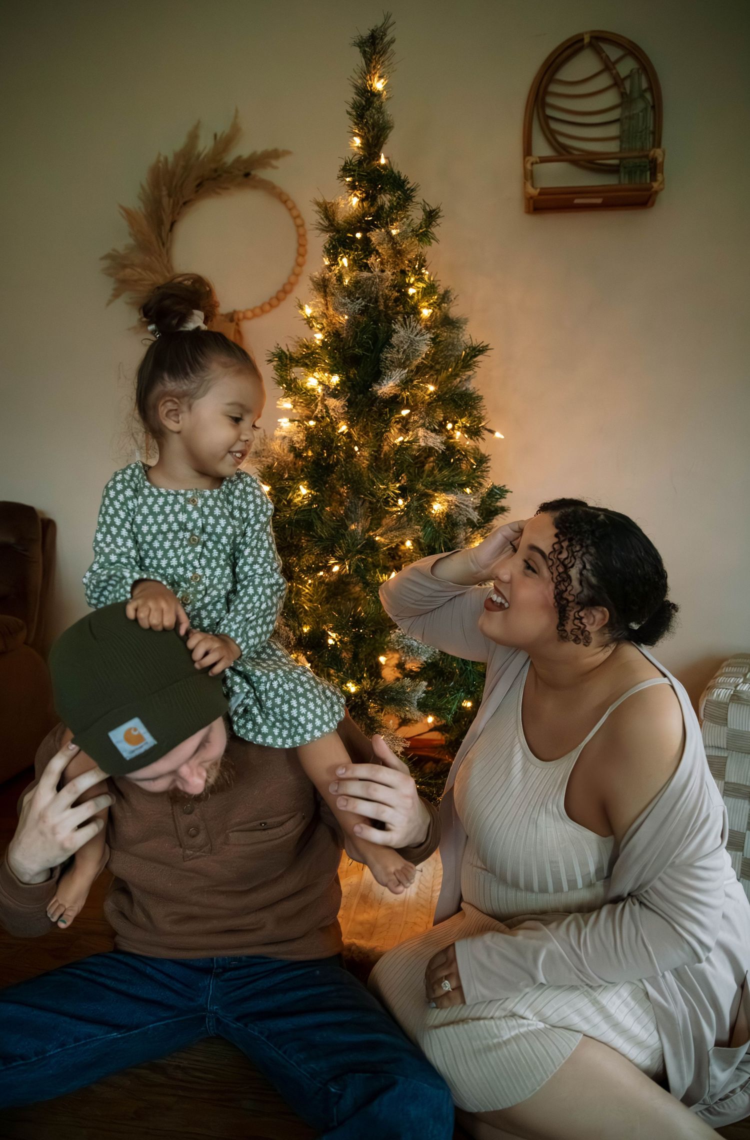 Family sharing joyful holiday moment in front of decorated Christmas tree with glowing lights and festive decor.