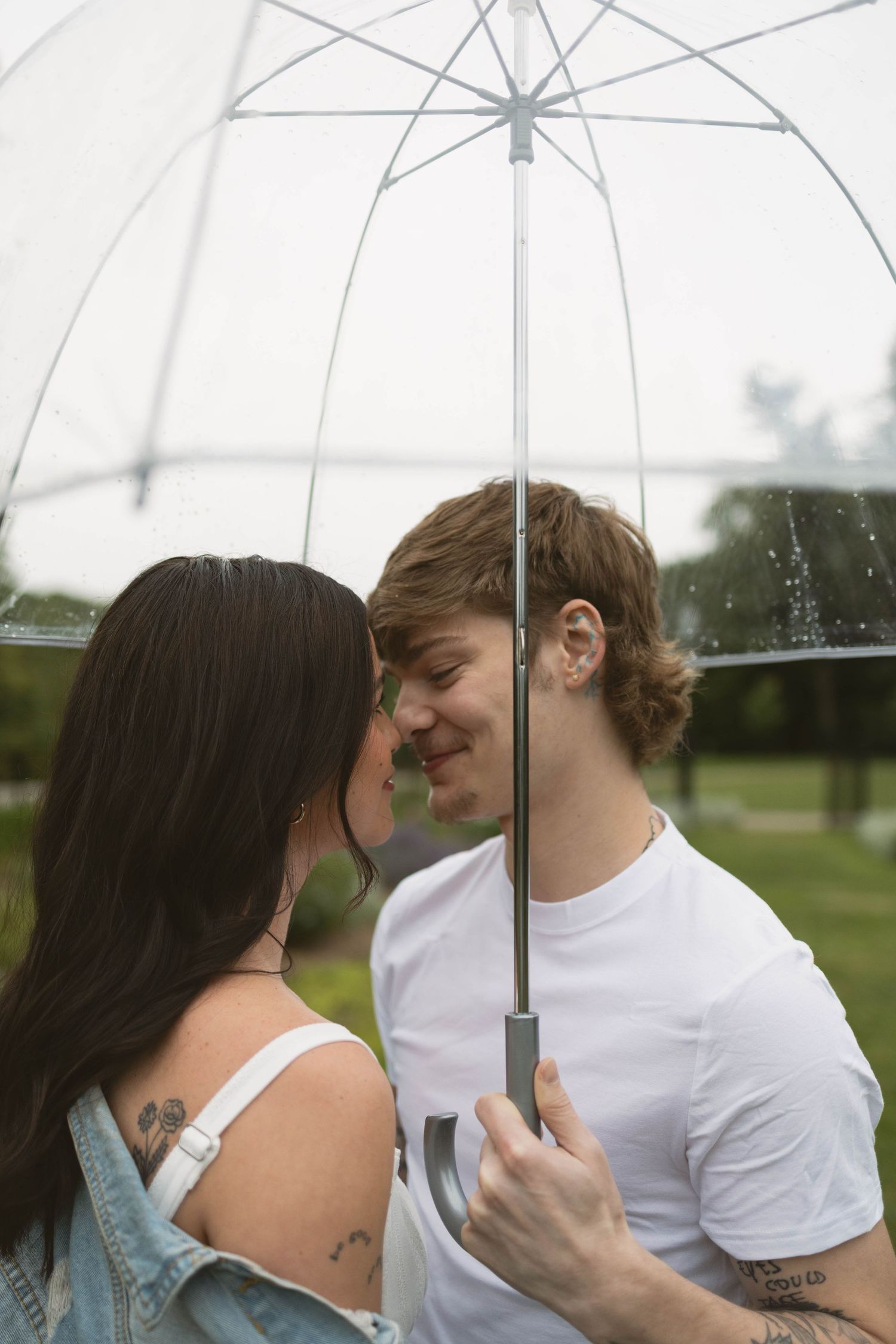 Romantic couple share intimate moments under a clear umbrella in a series of progressive shots outdoors.