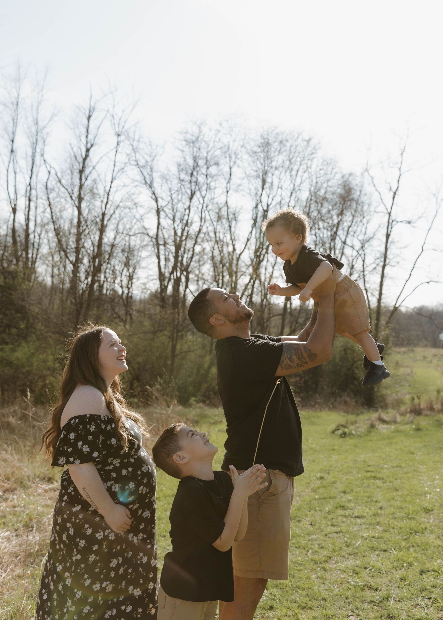People enjoying a sunny day outdoors in a grassy field with bare trees in the background.