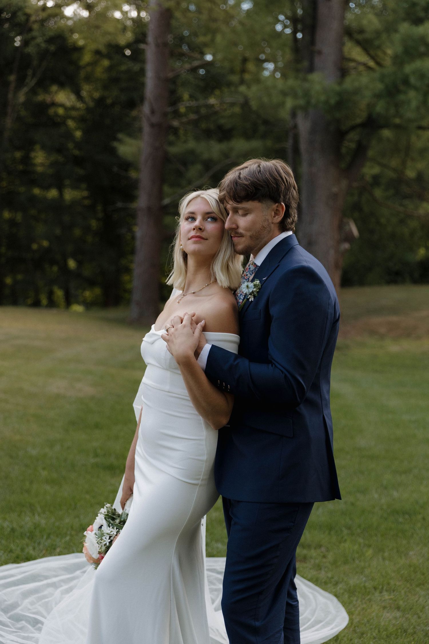 A couple shares an intimate moment on their wedding day in a lush outdoor garden setting with the bride in white.