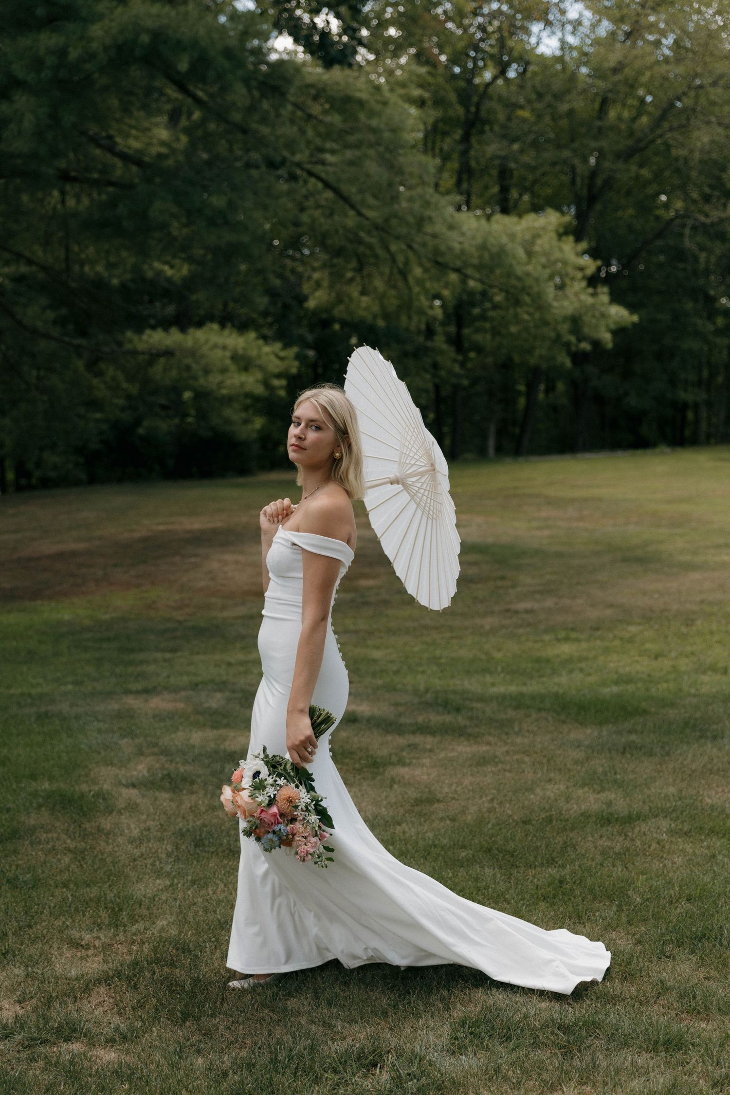 Romantic bridal photoshoot in a garden setting featuring a flowing white dress and parasol.