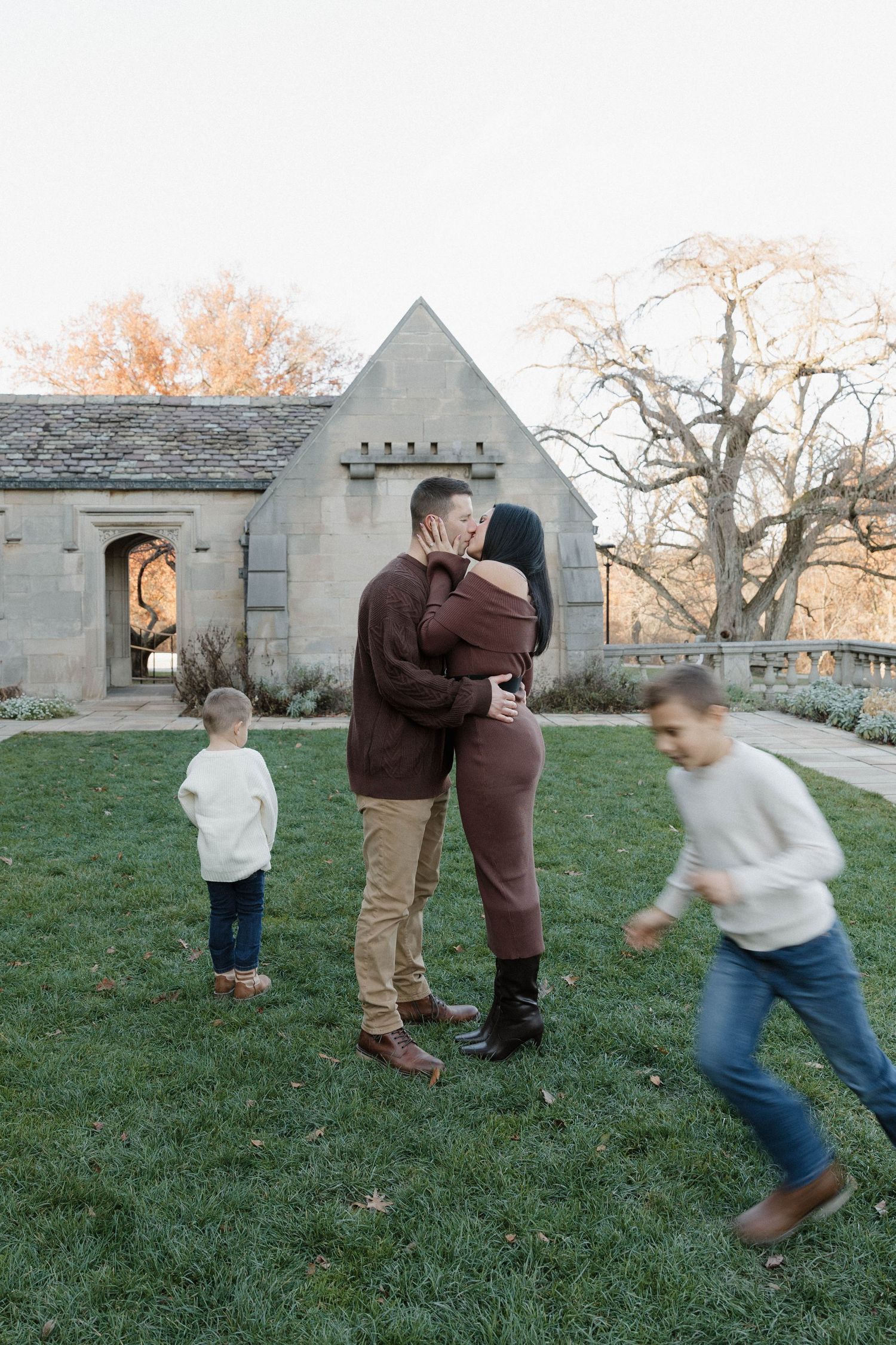 A sequence of images showing playful interaction between people on a grassy lawn near stone buildings at sunset.