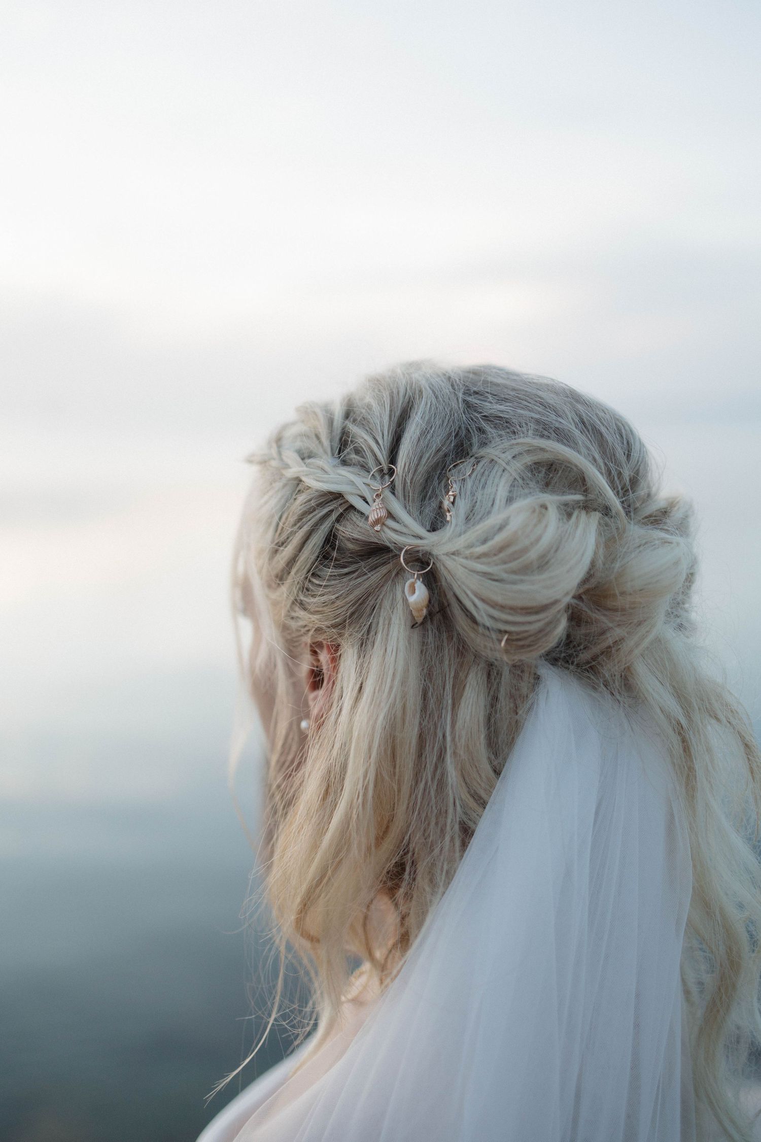 Bridal updo with braided bow hair accessory and veil, elegant wedding hairstyle for blonde hair.