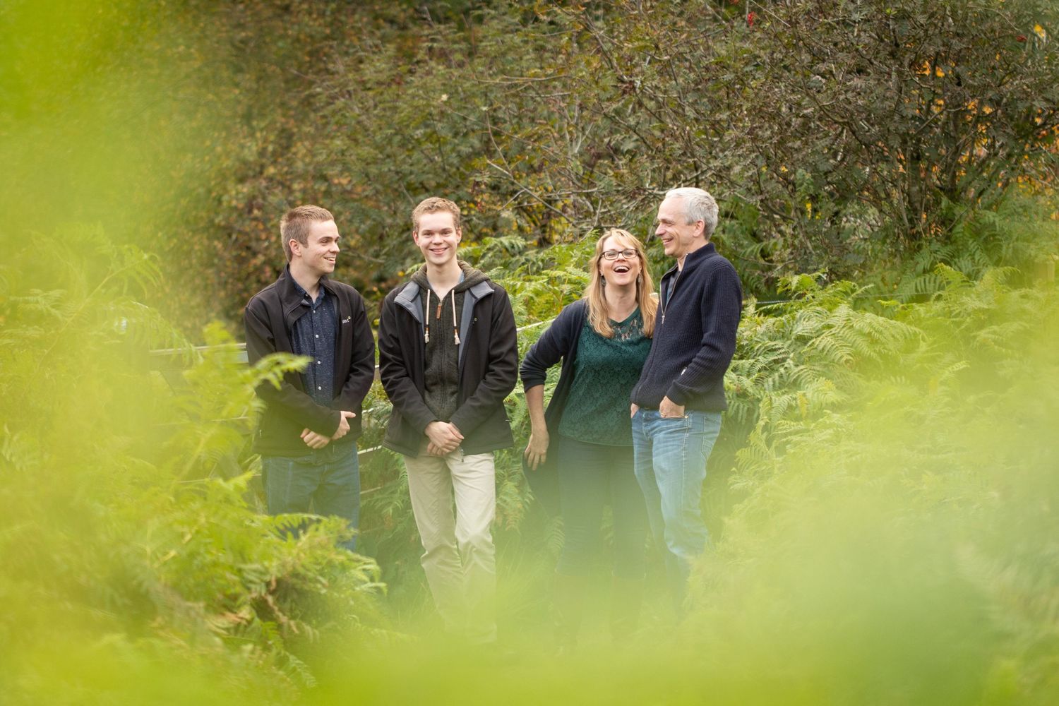 Small group poses together outdoors with green foliage framing the shot.