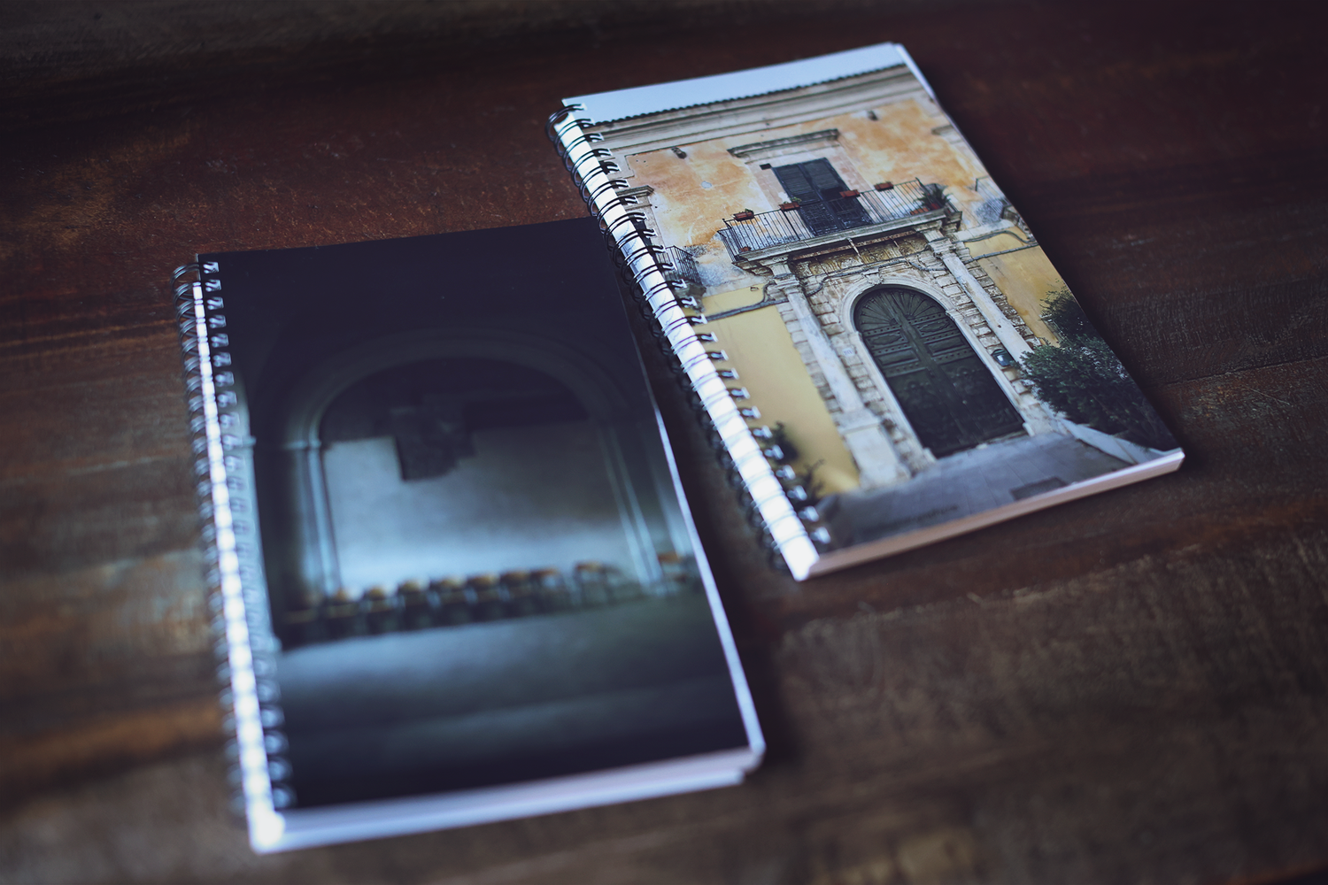 Black and white architectural photography images shown in spiral bound notebook pages on wooden surface.