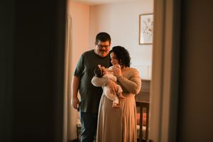 Two people sharing an intimate moment in a warmly lit room with peach-colored walls and natural lighting.