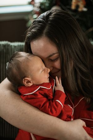 A tender moment between a mother and baby as they embrace, with the infant wearing a bright red outfit.