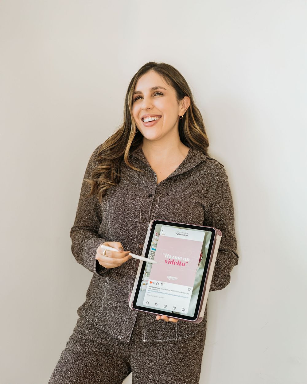 Woman in cozy gray loungewear holding tablet device displaying digital content.
