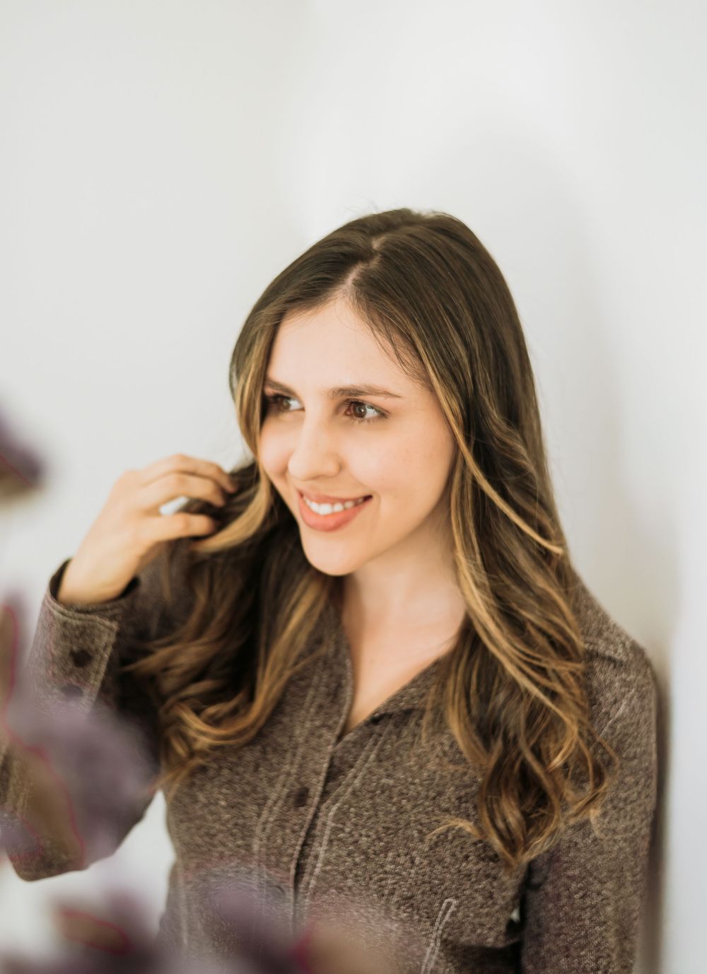 Portrait shot showing long wavy brown hair and a warm smile while wearing a brown knit sweater.