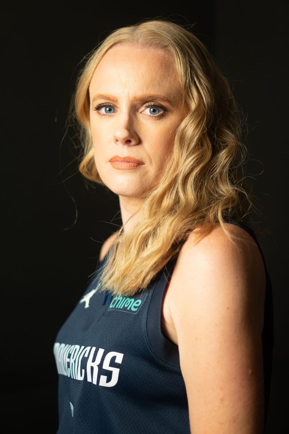 Athletic portrait of person in navy sports tank top against dark background.