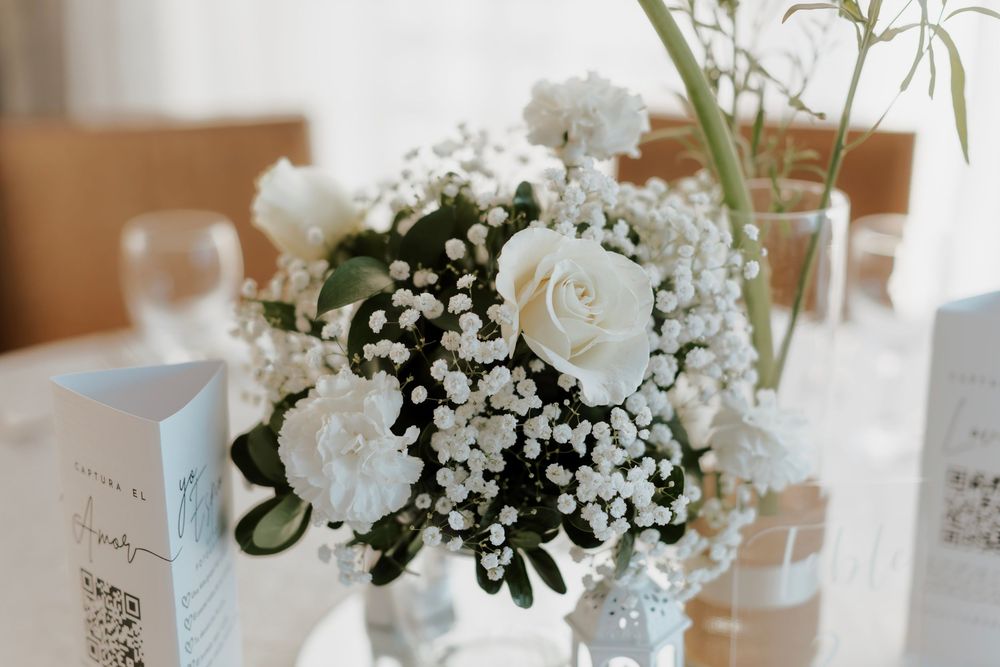 Elegant white roses and baby's breath floral centerpiece arrangement on a wedding table.