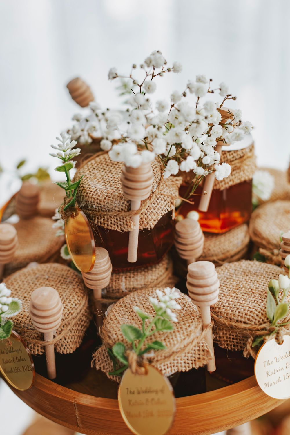 Honey jar wedding favors decorated with burlap, wooden dippers and delicate baby's breath flowers.