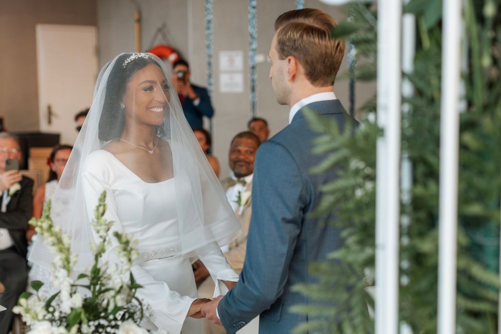 Wedding ceremony in progress under outdoor pavilion with greenery decorations.