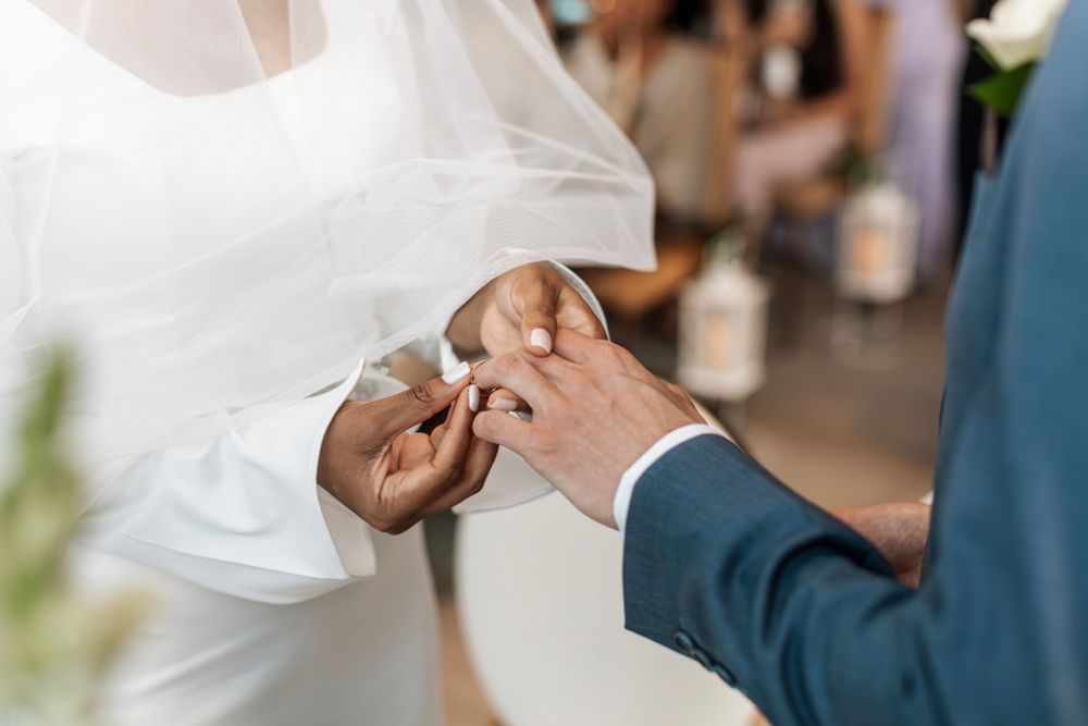 Close-up of hands exchanging wedding rings during ceremony.