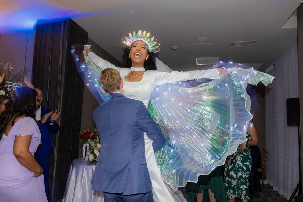 Dancing celebration at wedding reception with dramatic lighting and flowing dress.