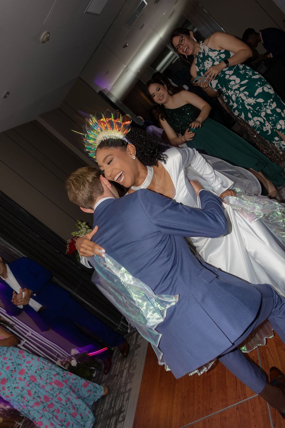 A couple dancing at their wedding reception with decorative lighting in the background.