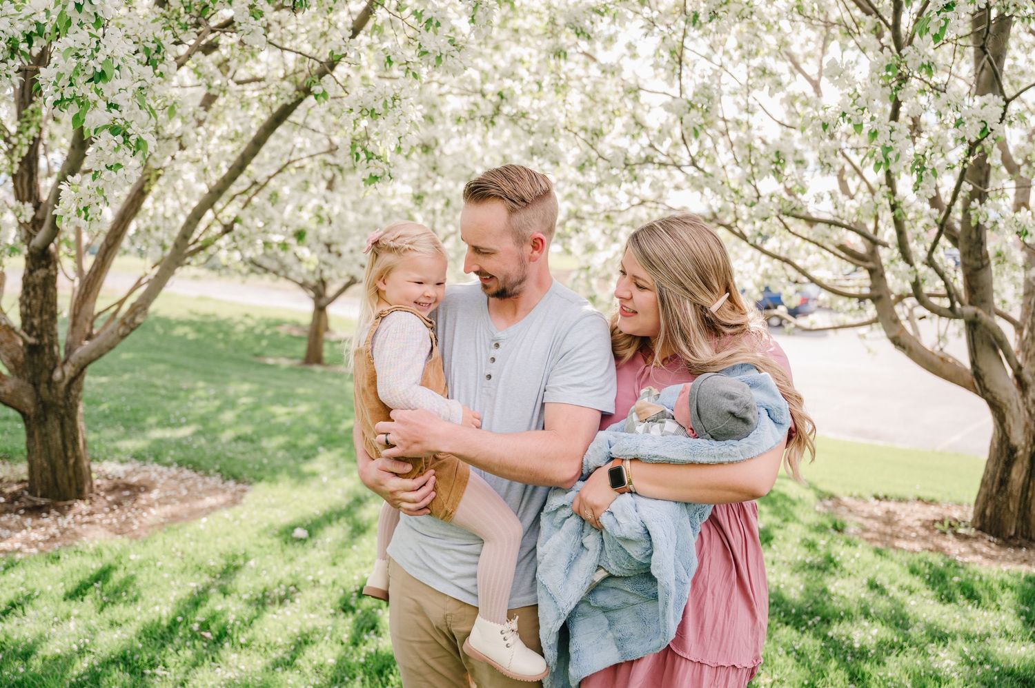 A family enjoying a tender moment together in a blooming spring garden with flowering trees.