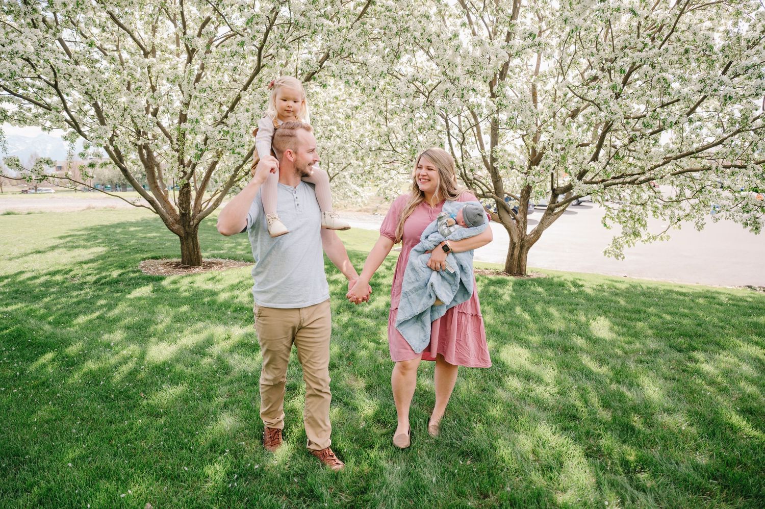 A couple enjoys a spring day under blooming white cherry blossom trees on a grassy lawn.