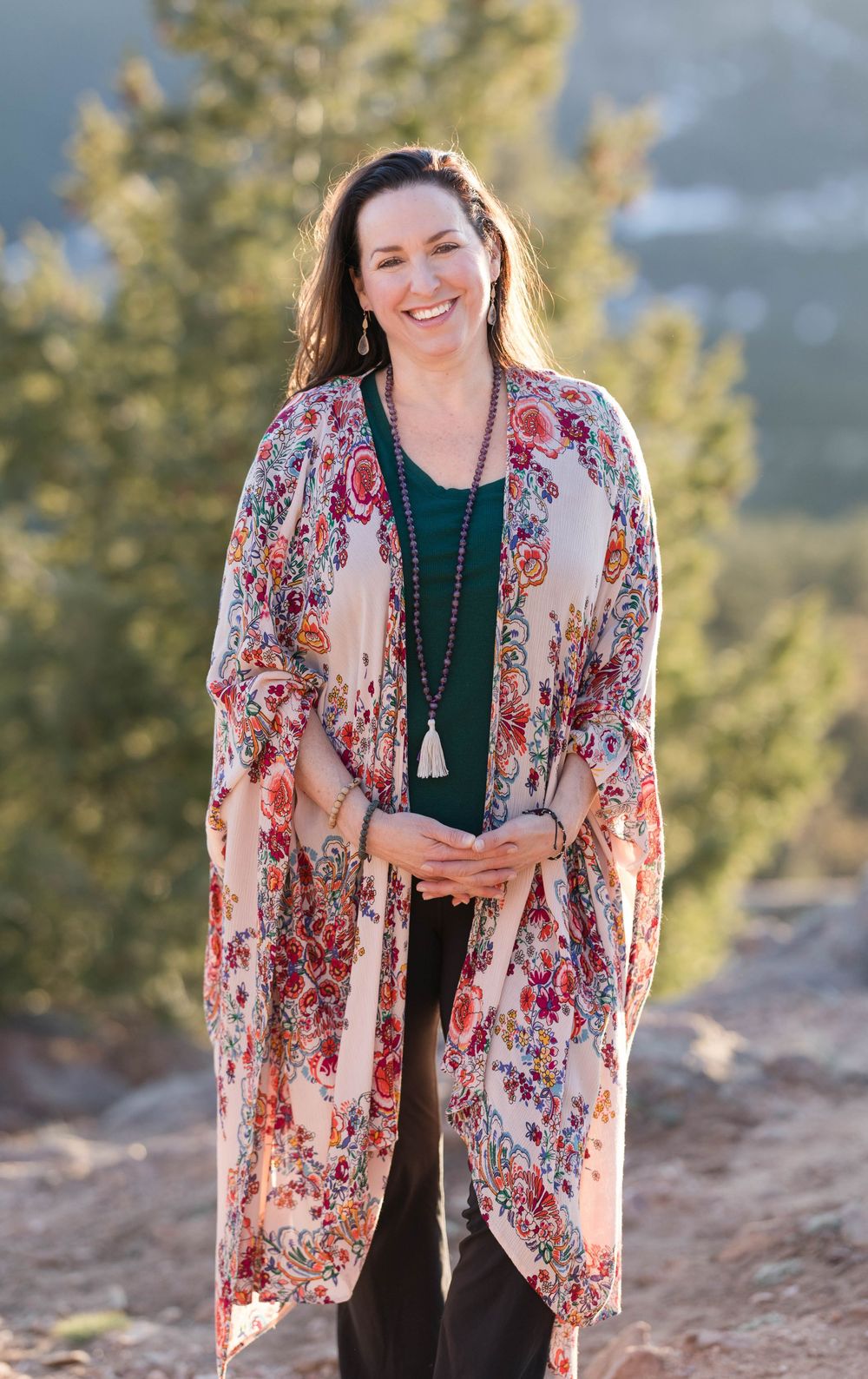 Floral kimono cardigan in cream and red tones paired with dark top and long pendant necklace in outdoor setting.