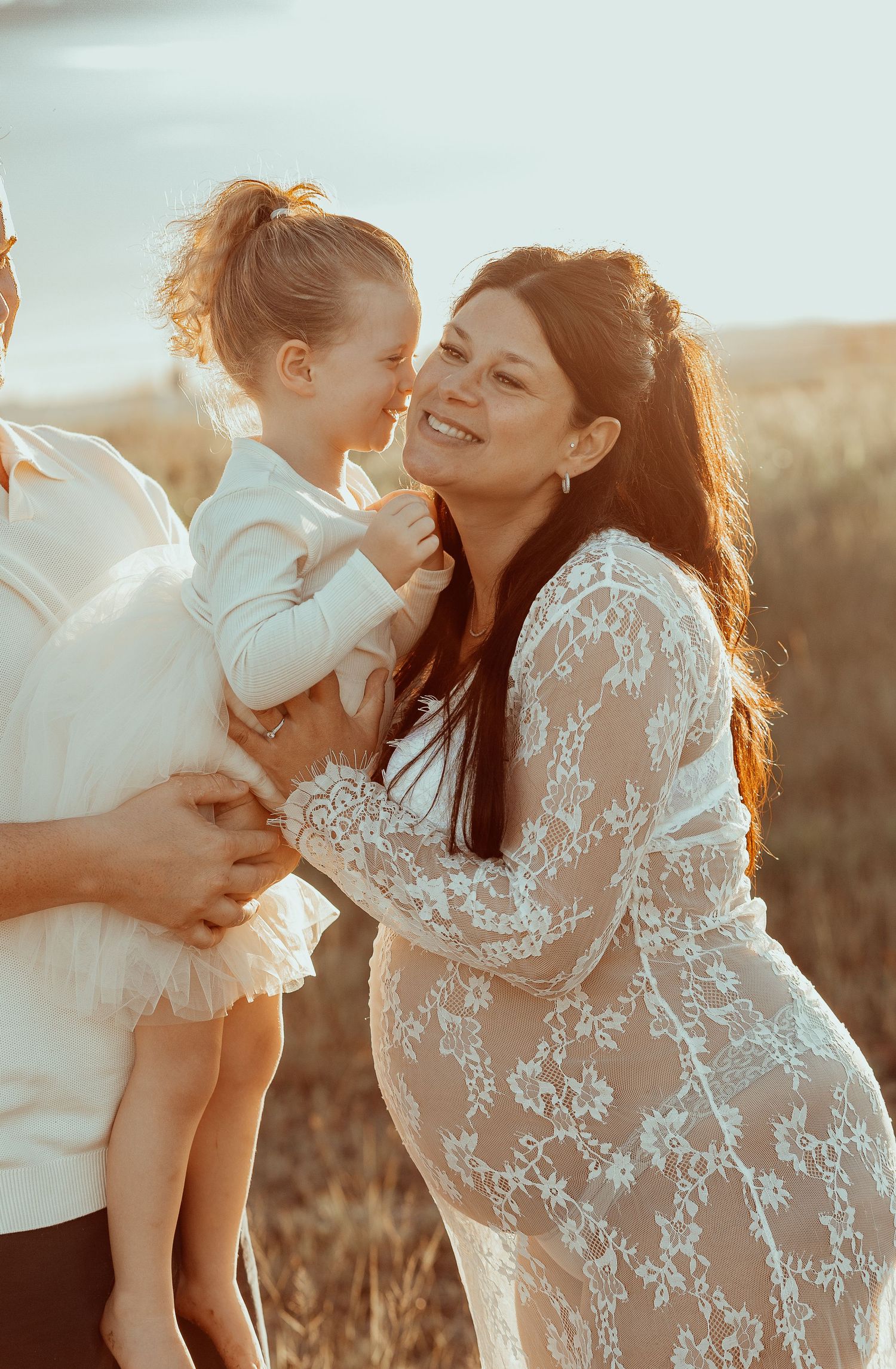 Intimate family moment captured during maternity photoshoot in golden sunset light.