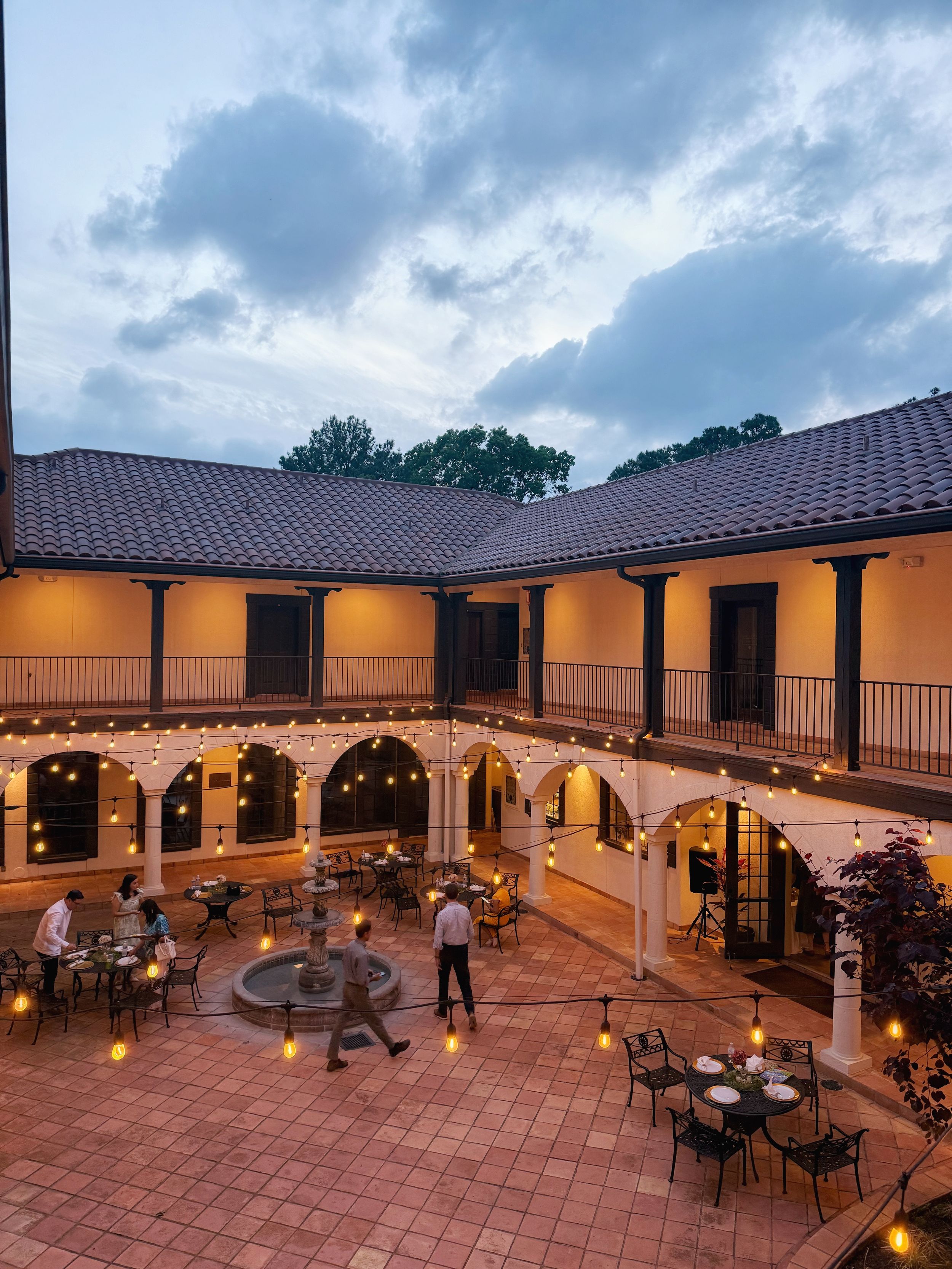 Evening dining at a Spanish-style courtyard restaurant with terra cotta tiles, arched columns and warm ambient lighting.