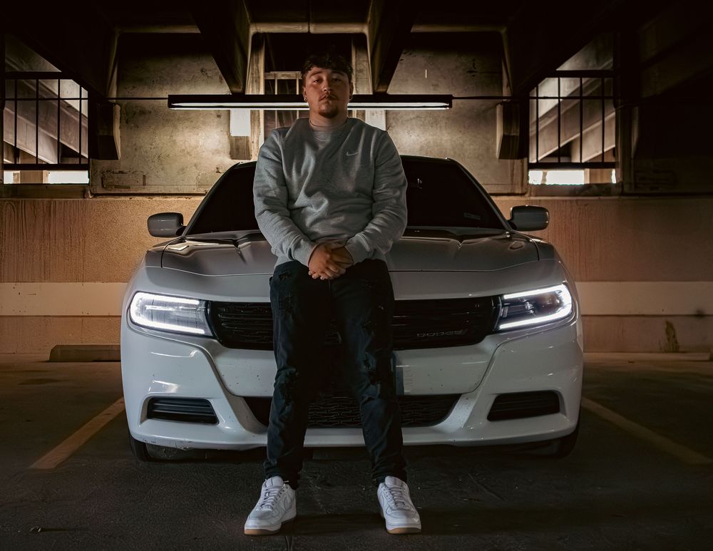 White Dodge Charger parked in dimly lit parking garage with LED headlights illuminated.